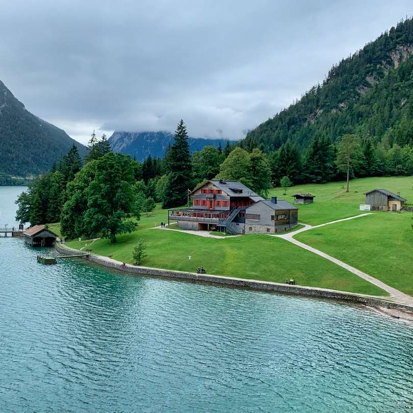 casă albă și roșie lângă lac și copaci verzi în timpul zilei puzzle online