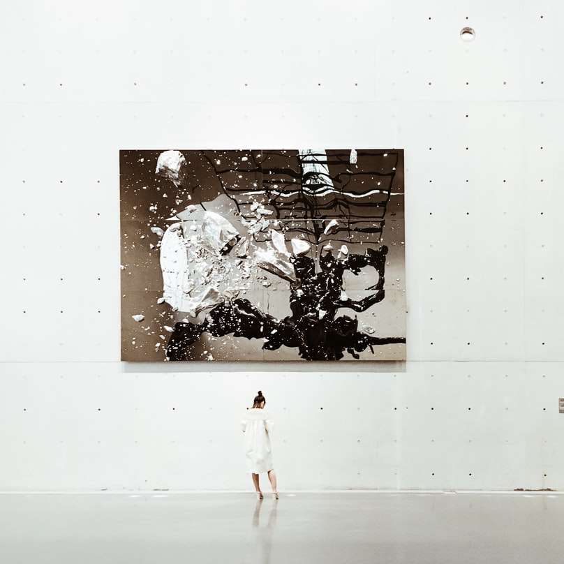 Eine Frau, die in einer Galerie für moderne Kunst in der Nähe eines Gemäldes steht Online-Puzzle