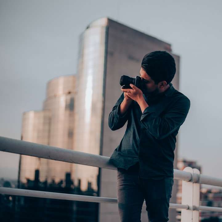 άνδρας με μαύρο πουκάμισο χρησιμοποιώντας κάμερα DSLR online παζλ