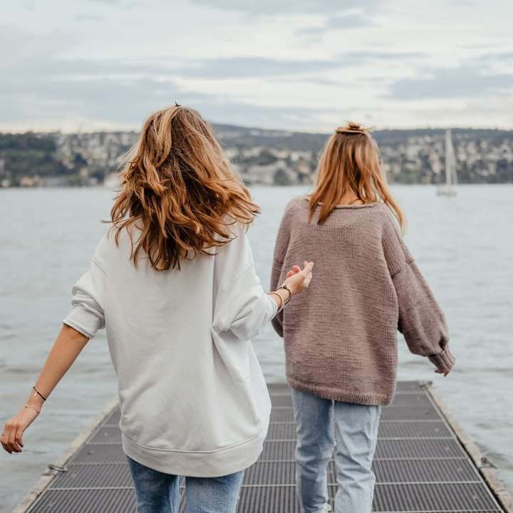 дві жінки, стоячи на доку перед морем вдень онлайн пазл