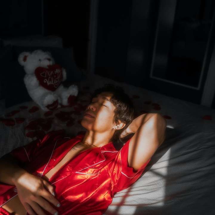 chica en camiseta sin mangas roja acostada en la cama puzzle deslizante online