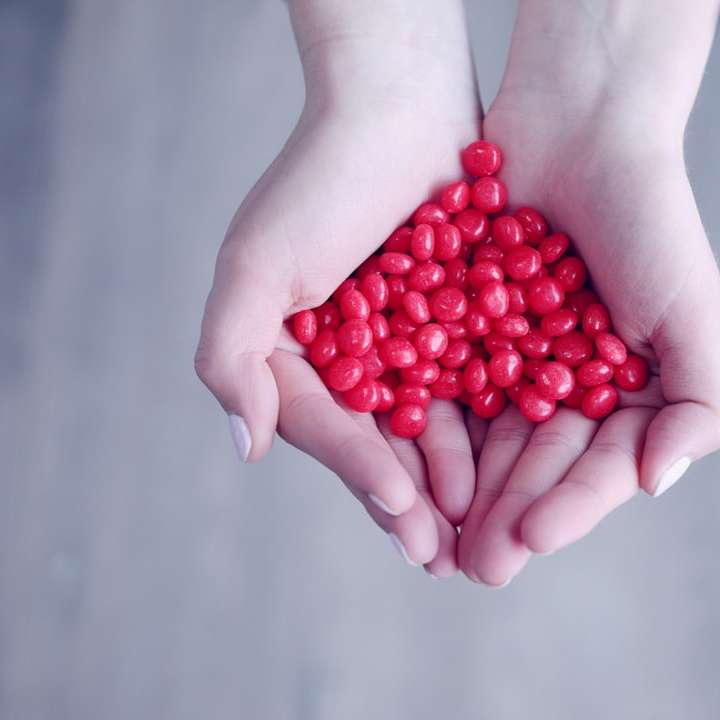 човек, който държи червени бонбони на дланите си плъзгащ се пъзел онлайн